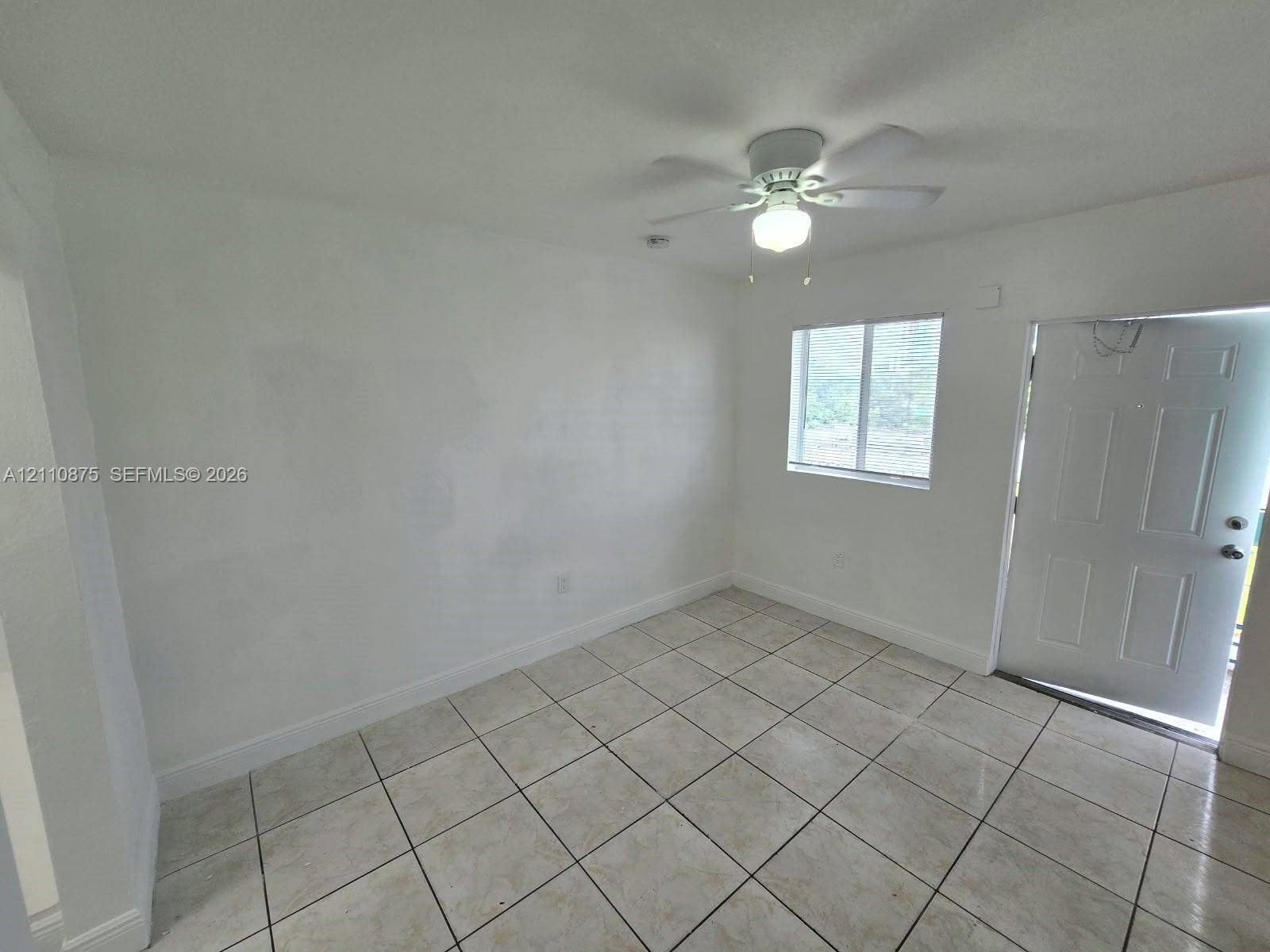 535 NW 7th Street, #10, Miami, Miami, FL 33136 Interior space featuring large-format neutral floor tiling, a multi-blade ceiling fan with an integrated light fixture, a single-panel window, and a white six-panel exterior door