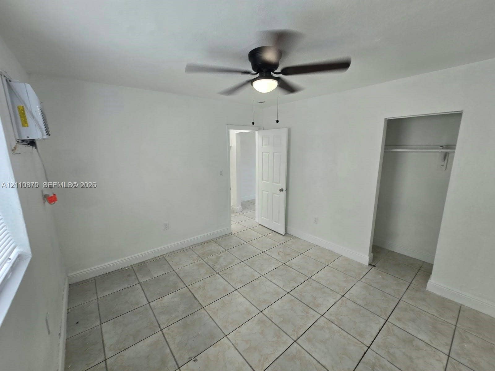 535 NW 7th Street, #10, Miami, Miami, FL 33136 Room featuring neutral-toned tile flooring, a multi-blade ceiling fan with integrated lighting, and an inset closet with a built-in hanging rod