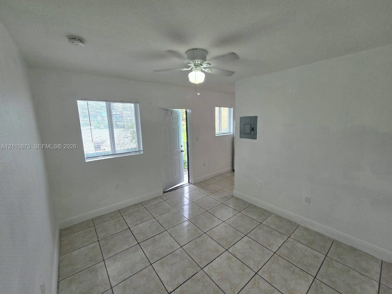 535 NW 7th Street, #10, Miami, Miami, FL 33136 Interior space featuring neutral wall tones, large-format ceramic tile flooring, a ceiling-mounted fan with integrated lighting, and multiple windows providing natural illumination