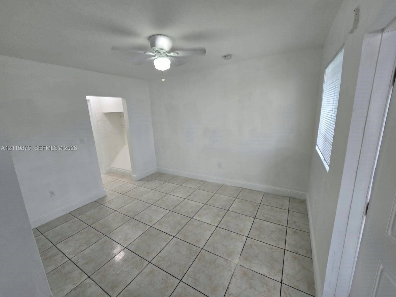 535 NW 7th Street, #10, Miami, Miami, FL 33136 Neutral interior space featuring ceramic tile flooring, a white ceiling fan with integrated light fixture, and horizontal blind window treatments