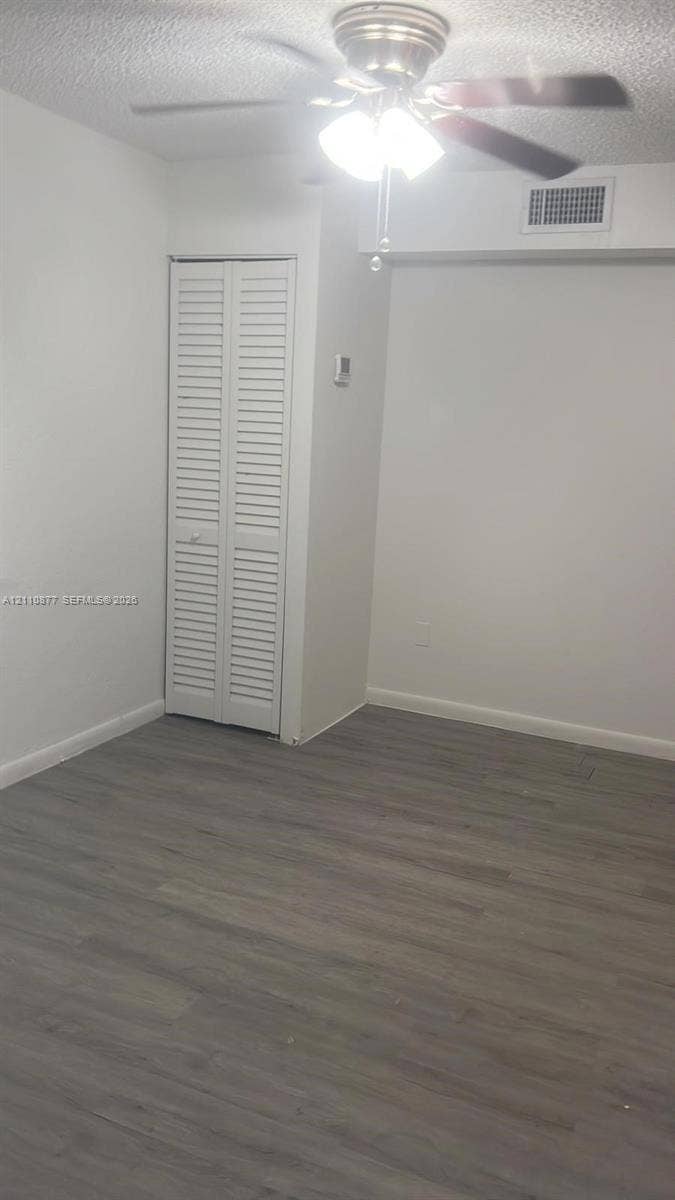 7230 NW 3rd Street, #4, Miami, Miami, FL 33126 Interior space featuring wood-finish flooring, a white bi-fold closet door, and a ceiling fan with integrated lighting