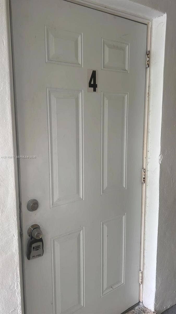 7230 NW 3rd Street, #4, Miami, Miami, FL 33126 White six-panel entry door featuring a dual-lock system and door-mounted number plate