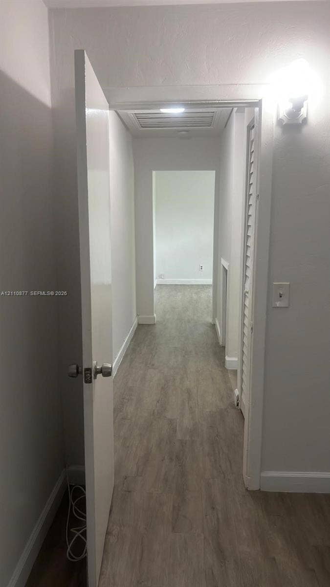 7230 NW 3rd Street, #4, Miami, Miami, FL 33126 Hallway featuring wood-finish flooring, ceiling-mounted lighting, and a louvered closet door