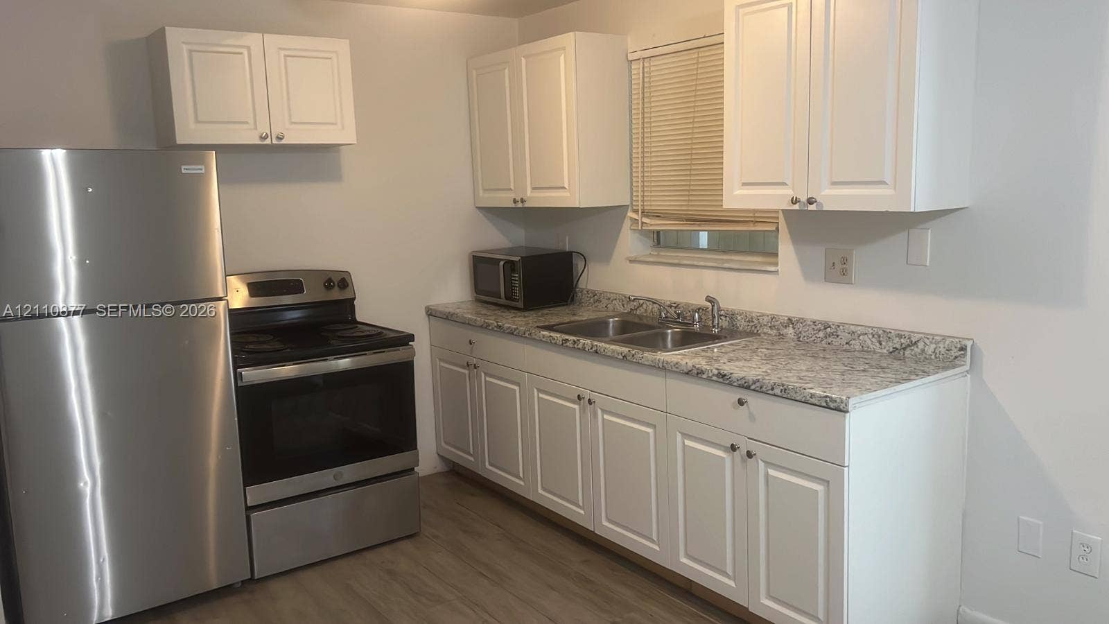 7230 NW 3rd Street, #4, Miami, Miami, FL 33126 Kitchen featuring white shaker-style cabinetry, patterned stone-finish countertops, dual-basin stainless steel sink, and stainless steel appliances