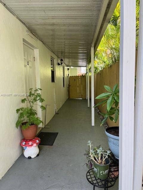 7230 NW 3rd Street, #4, Miami, Miami, FL 33126 Covered exterior walkway featuring a concrete floor, support pillars, wall-mounted light fixture, and wooden privacy fencing