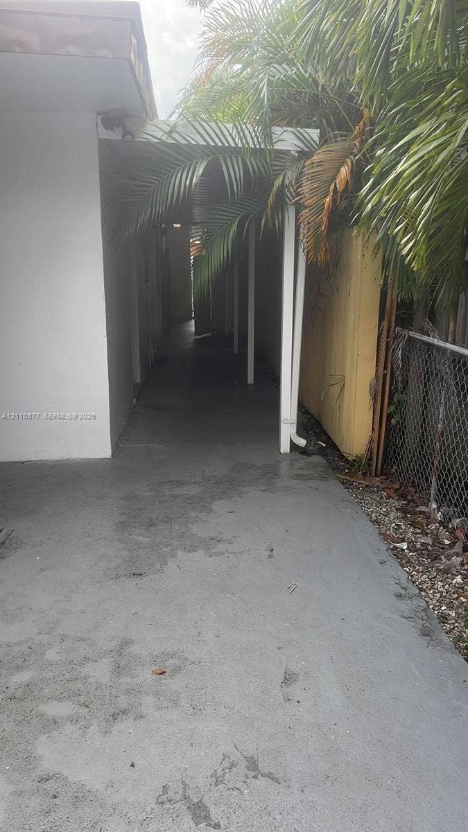 7230 NW 3rd Street, #4, Miami, Miami, FL 33126 Covered exterior walkway featuring a concrete path, structural support posts, and perimeter fencing