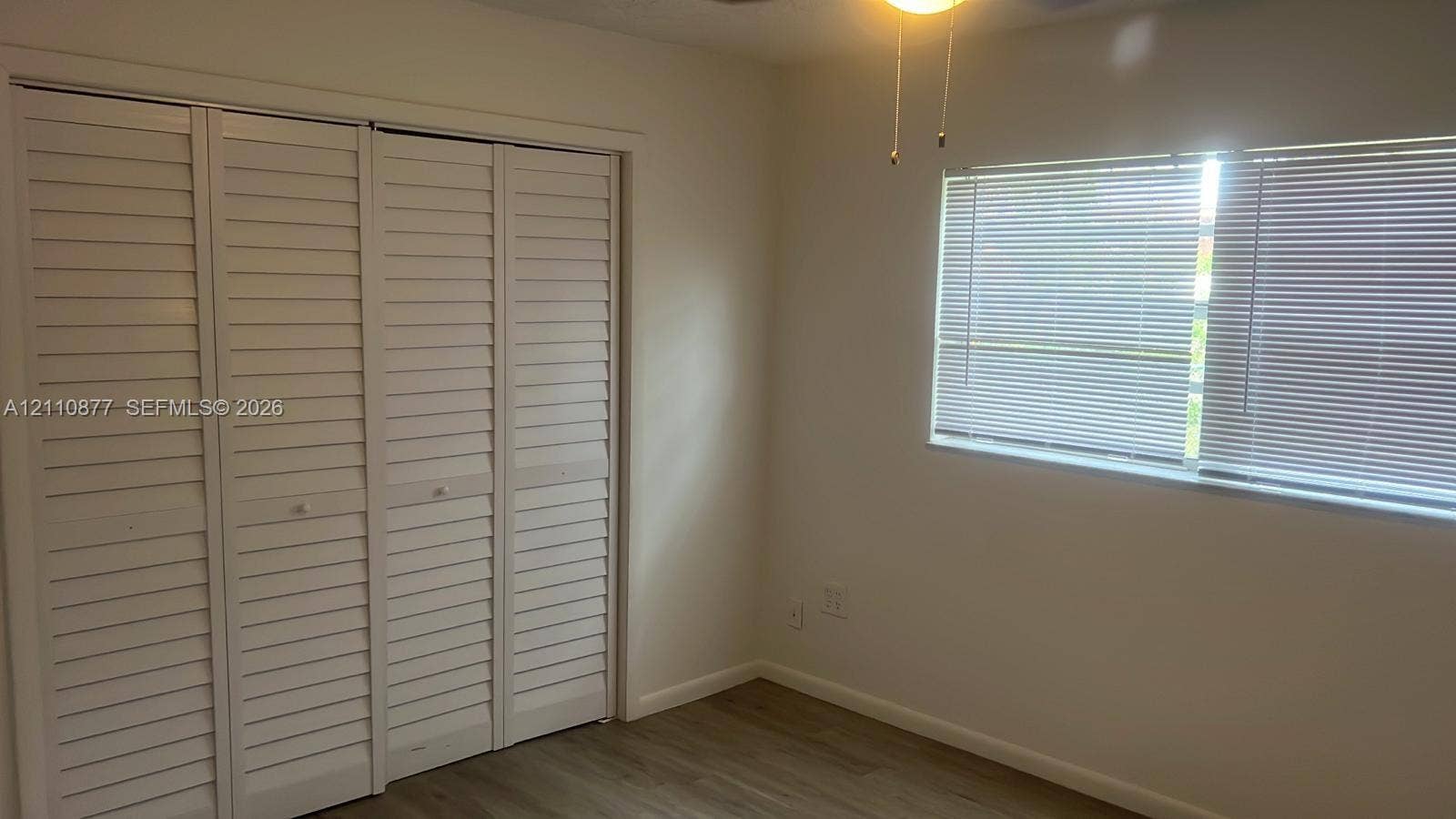 7230 NW 3rd Street, #4, Miami, Miami, FL 33126 Room featuring four-panel louvered closet doors, wood-finish flooring, and a ceiling-mounted light fixture