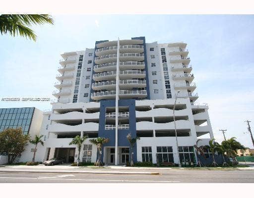 2600 SW 27th Avenue, #702, Miami, FL 33133 Multi-story concrete high-rise exterior featuring private cantilevered balconies, blue architectural accent panels, and ground-level palm tree landscaping