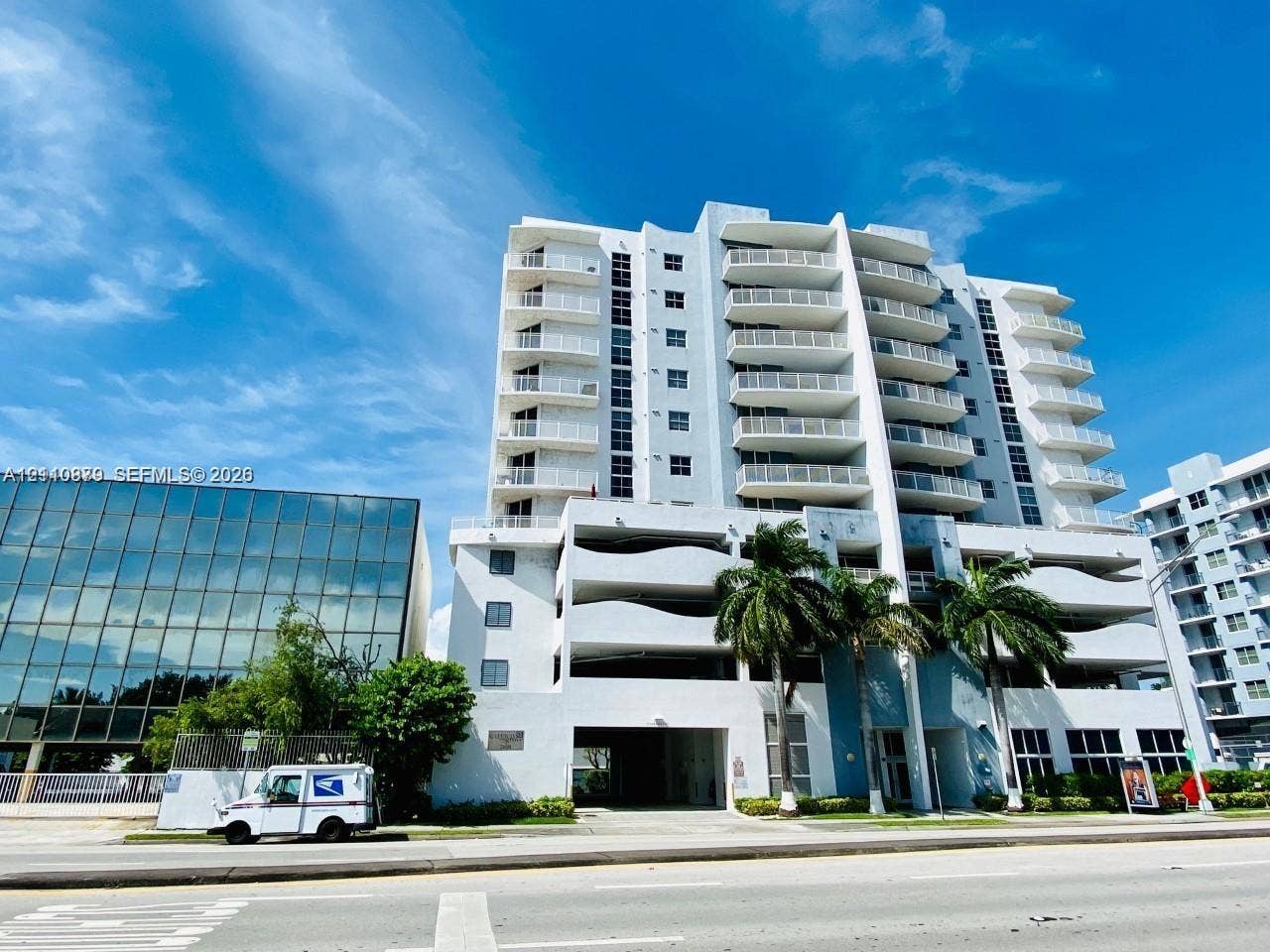 2600 SW 27th Avenue, #702, Miami, FL 33133 Mid-rise concrete exterior featuring stacked balconies, integrated covered parking levels, and mature palm tree landscaping