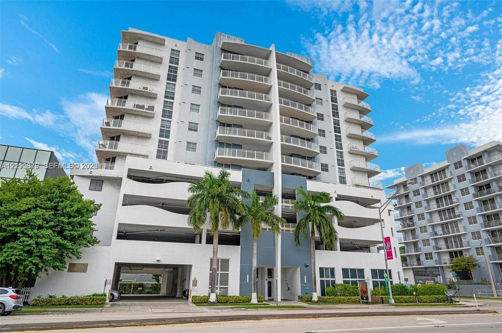 2600 SW 27th Avenue, #702, Miami, FL 33133 High-rise residential exterior featuring private balconies, integrated parking structure, and palm tree landscaping