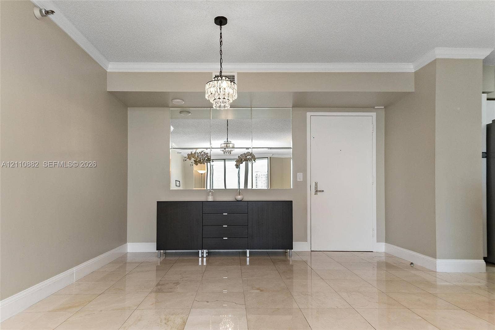Polished stone tile flooring, multi-pane wall mirror, and crystal-style chandelier lighting