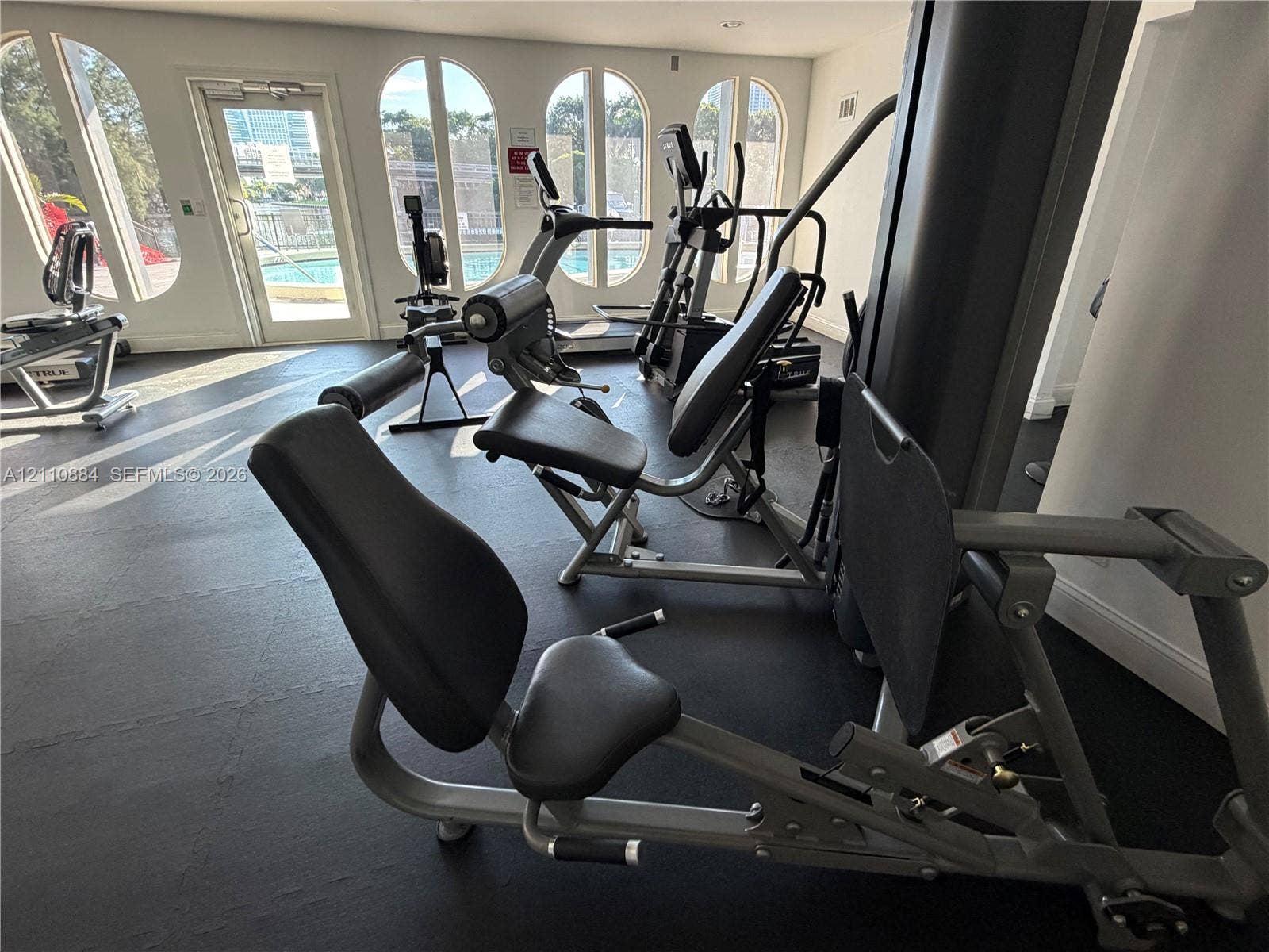 400 Diplomat Parkway, #805, Hallandale Beach, FL 33009 Fitness center featuring arched windows, dark rubberized flooring, and glass-paneled entry door