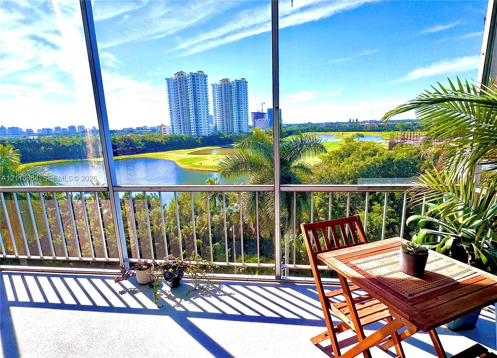 400 Diplomat Parkway, #805, Hallandale Beach, FL 33009 Screen-enclosed balcony featuring a metal railing, overlooking a water feature and manicured landscape