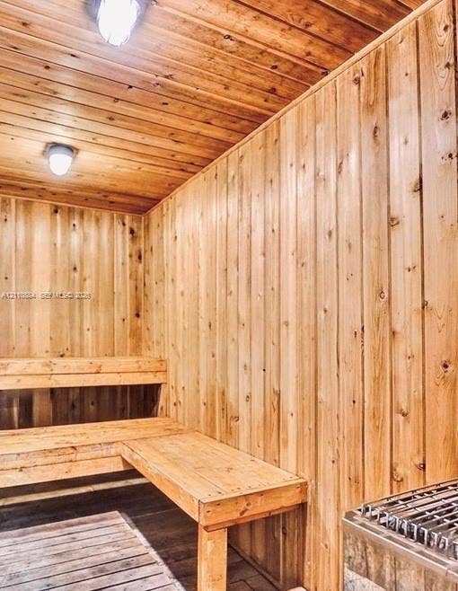 400 Diplomat Parkway, #805, Hallandale Beach, FL 33009 Sauna featuring natural wood-paneled walls and ceiling, built-in tiered wooden benches, slatted wooden floor decking, and stainless steel heater unit with wall-mounted lighting