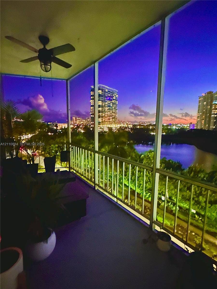 400 Diplomat Parkway, #805, Hallandale Beach, FL 33009 Screened-in balcony featuring a ceiling-mounted fan and metal railing, overlooking water and urban skyline