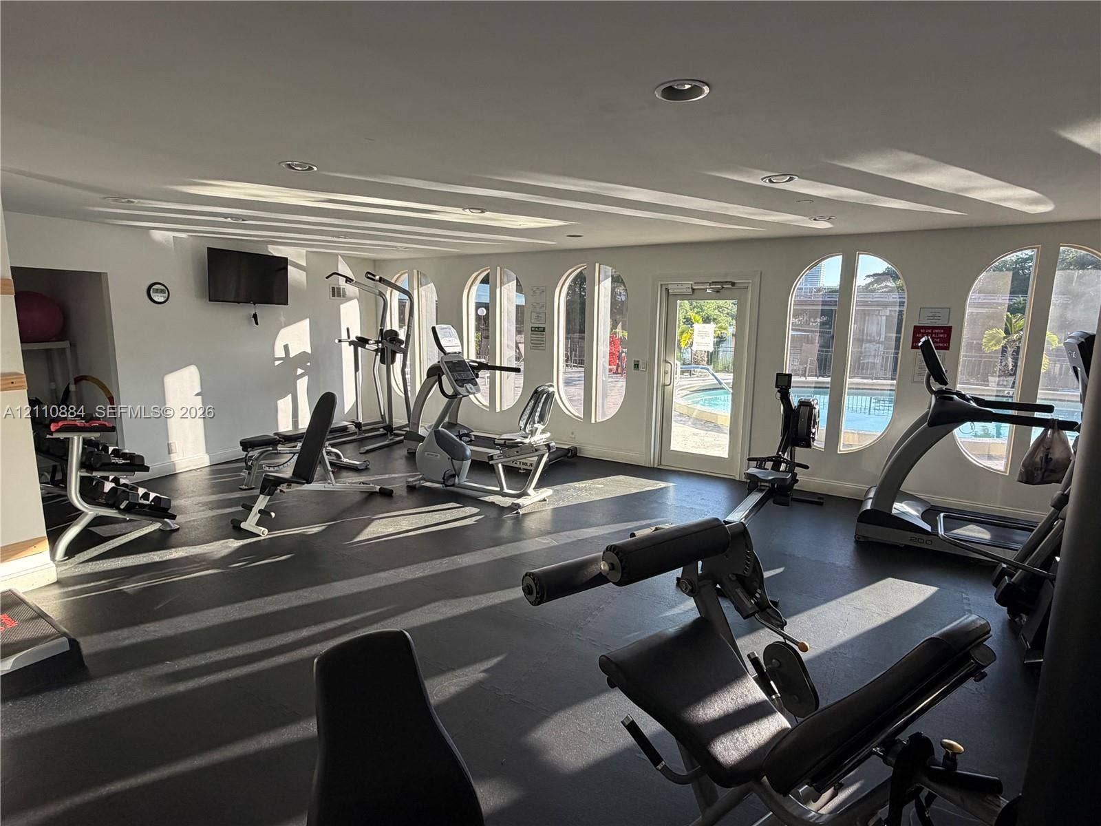 400 Diplomat Parkway, #805, Hallandale Beach, FL 33009 Fitness center featuring rubber flooring, recessed lighting, and arched windows with exterior pool access
