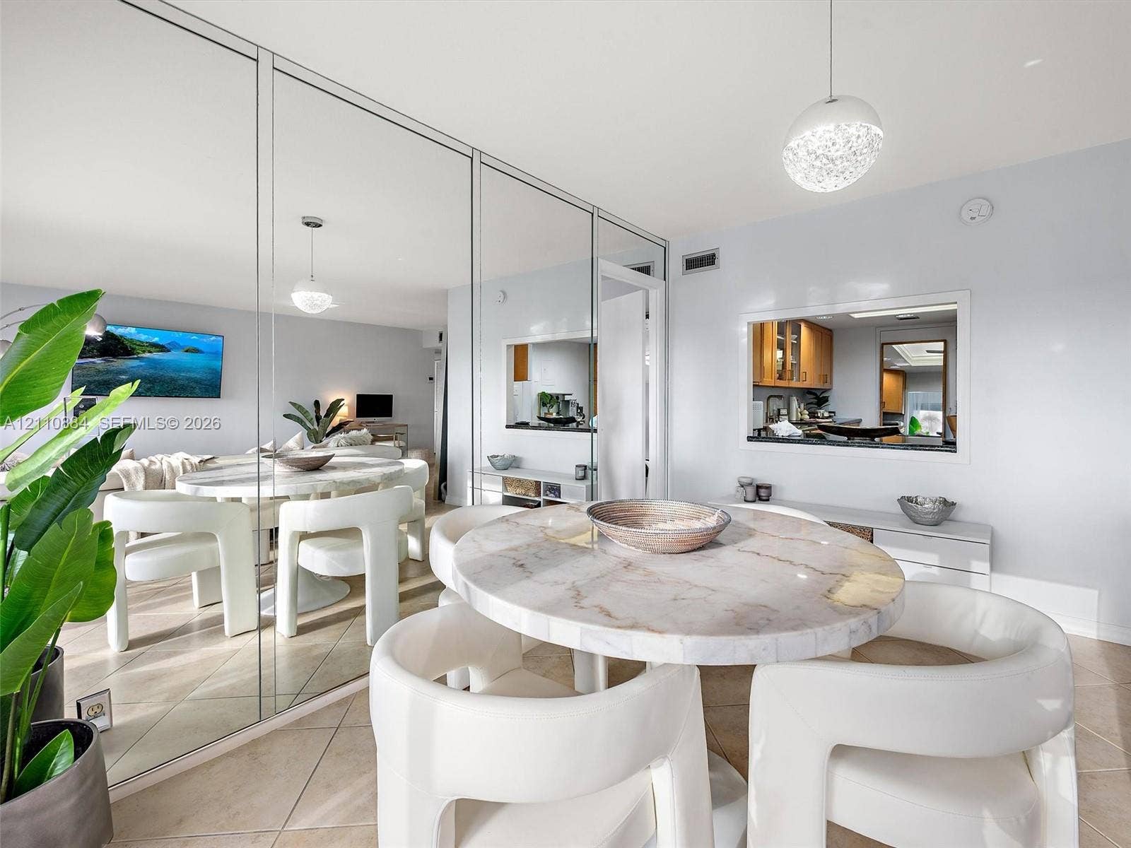 400 Diplomat Parkway, #805, Hallandale Beach, FL 33009 Full-wall mirrored accent, tile flooring, built-in kitchen pass-through window, and contemporary spherical pendant lighting