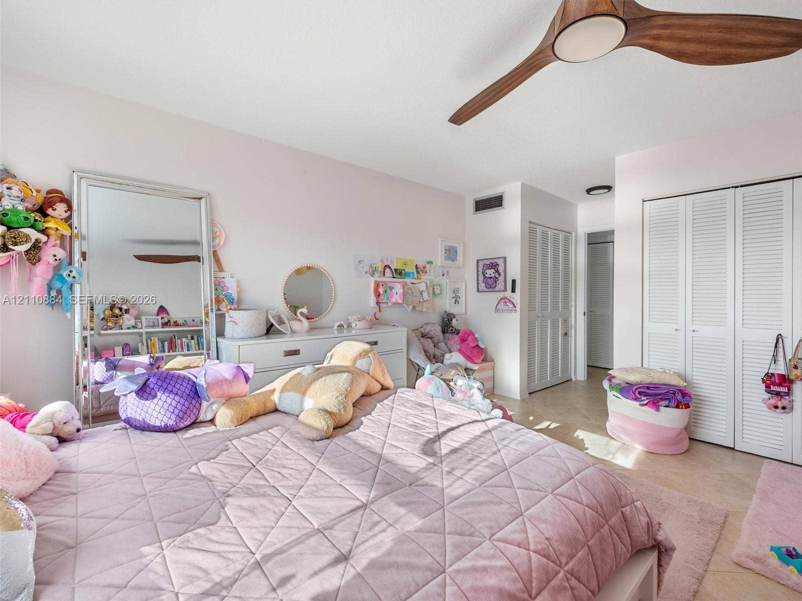 400 Diplomat Parkway, #805, Hallandale Beach, FL 33009 Bedroom featuring neutral-toned tile flooring, dual sets of bi-fold louvered closet doors, and a wood-finish ceiling fan with integrated lighting