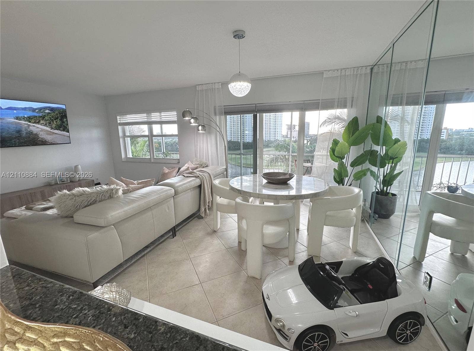 400 Diplomat Parkway, #805, Hallandale Beach, FL 33009 Open-concept interior featuring large-format ceramic tile flooring, floor-to-ceiling mirrored wall showcasing panoramic views with access to an exterior balcony