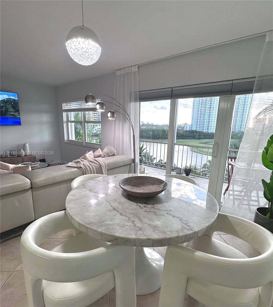 400 Diplomat Parkway, #805, Hallandale Beach, FL 33009 Open-concept interior featuring oversized tile flooring, recessed window treatments, a spherical pendant light fixture, and brand new impact rated floor-to-ceiling glass sliding doors opening to an exterior balcony