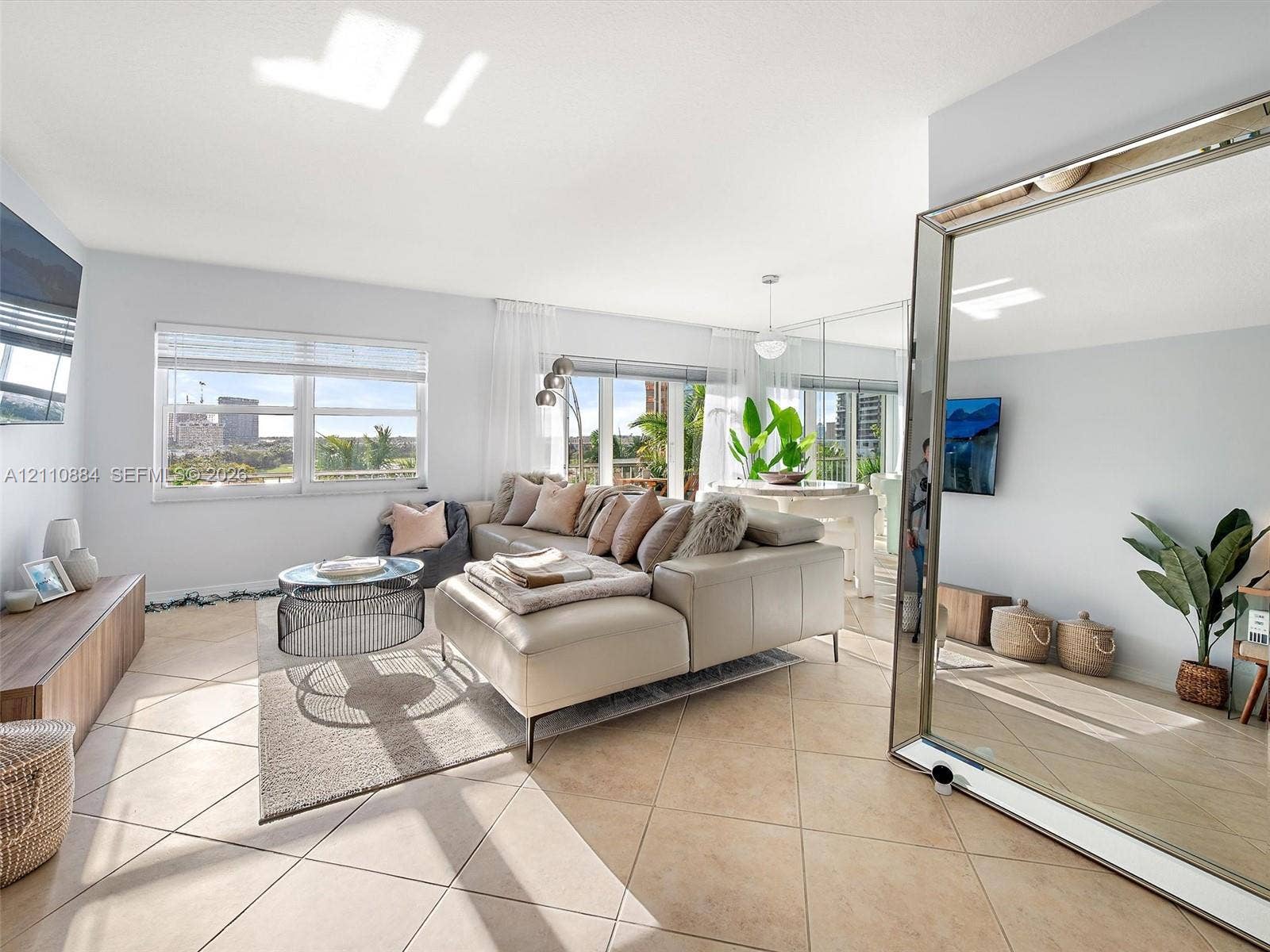 400 Diplomat Parkway, #805, Hallandale Beach, FL 33009 Open-concept living space featuring large-format ceramic tile flooring, expansive windows with exterior cityscape, and wall-to-wall mirror paneling