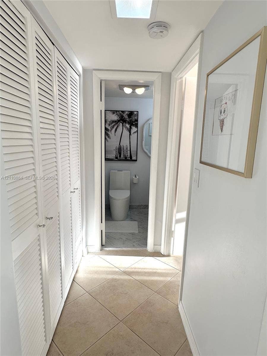 400 Diplomat Parkway, #805, Hallandale Beach, FL 33009 Hallway featuring floor-to-ceiling white louvered closet doors, neutral tile flooring and a newly renovated XXL closet space