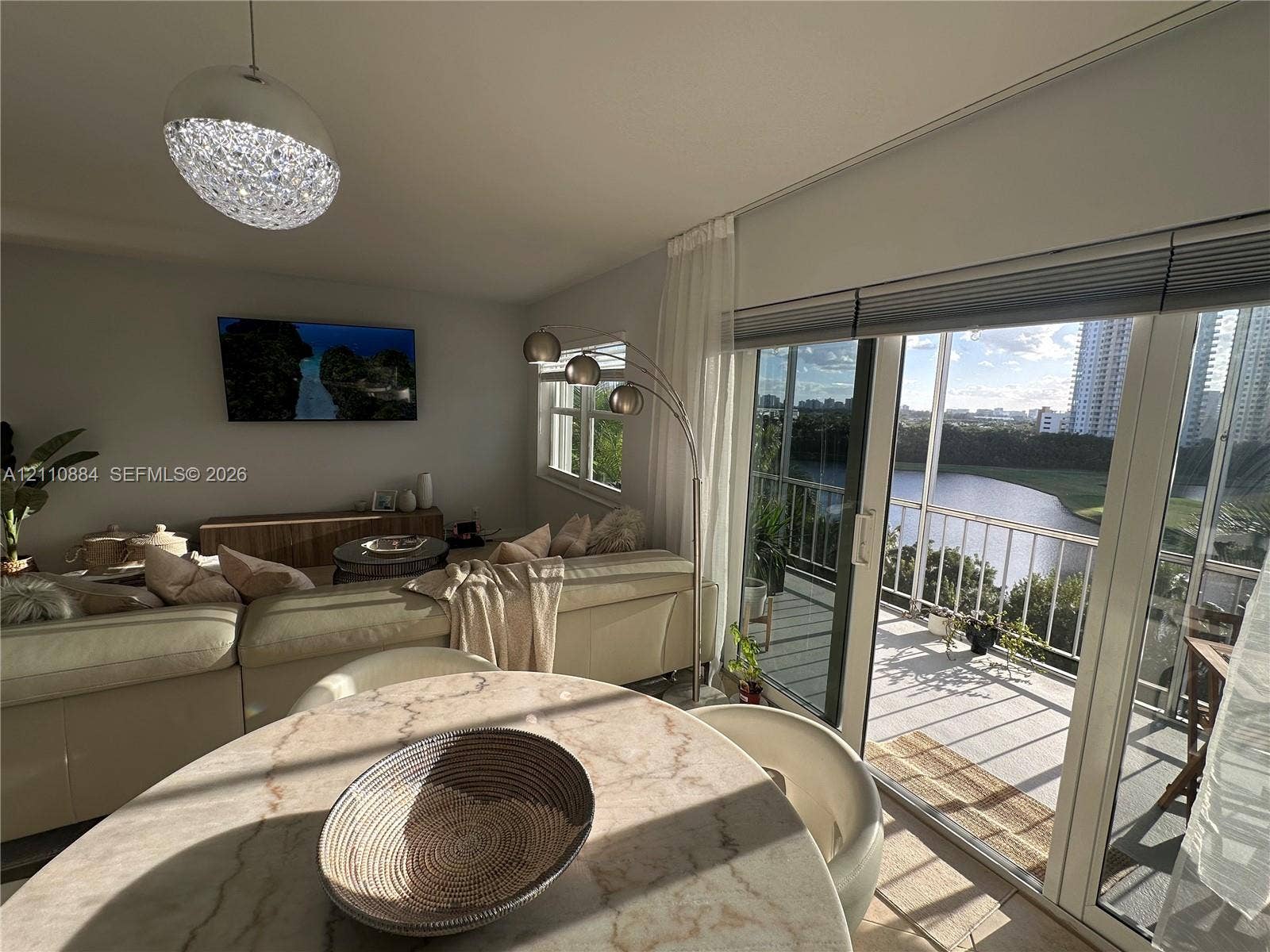 400 Diplomat Parkway, #805, Hallandale Beach, FL 33009 Living area featuring sliding glass doors to a balcony, floor-to-ceiling windows, and a decorative dome pendant light
