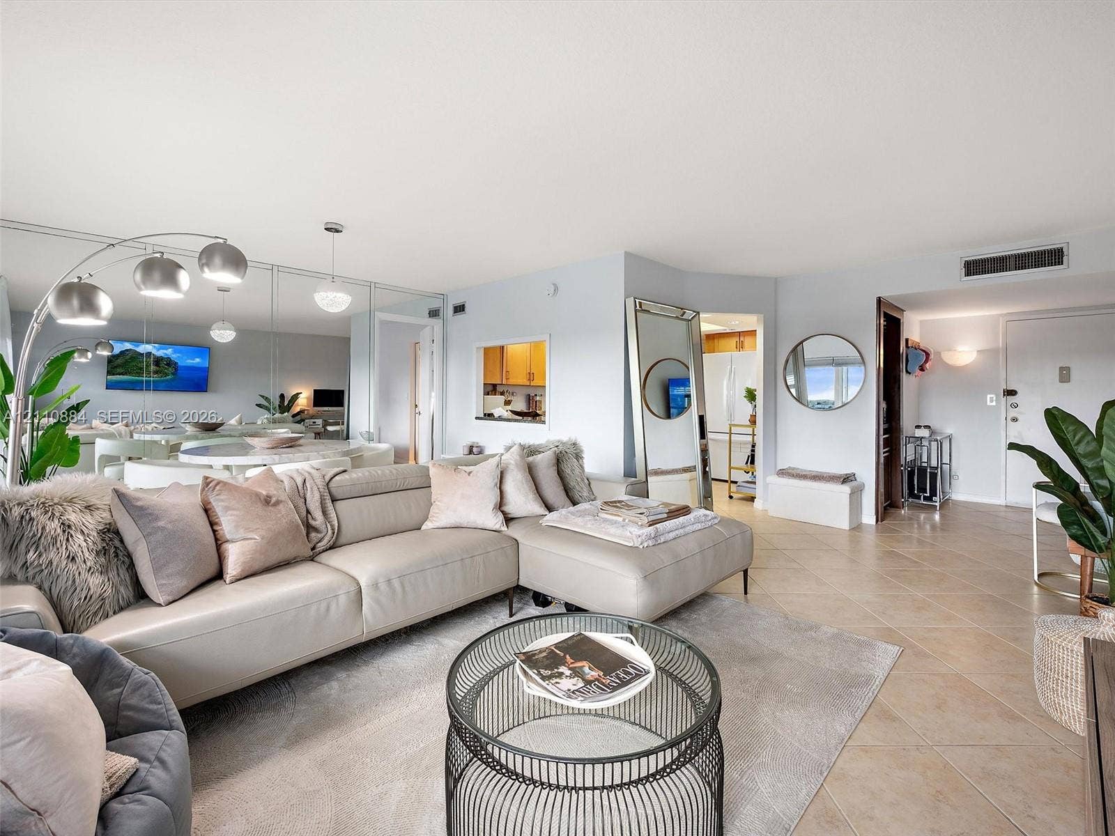 400 Diplomat Parkway, #805, Hallandale Beach, FL 33009 Living area featuring large-format ceramic tile flooring, mirrored wall paneling, and an architectural interior pass-through window