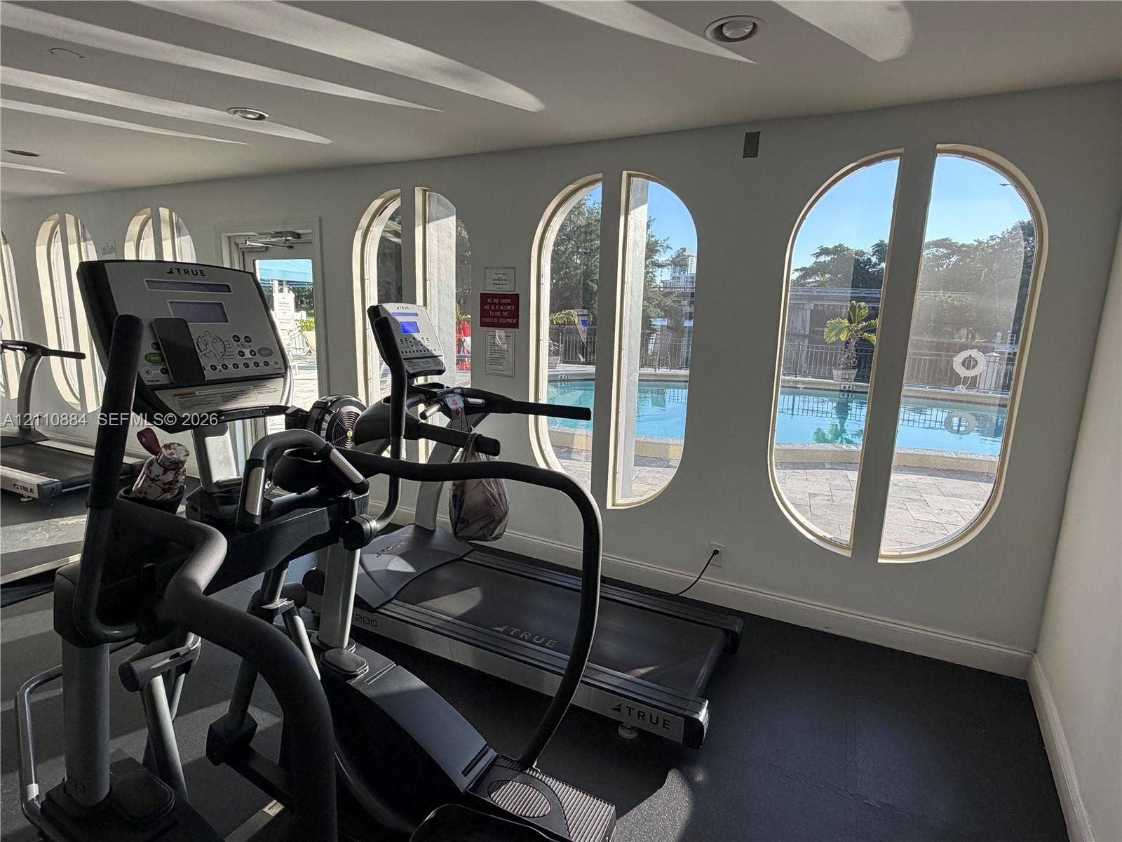 400 Diplomat Parkway, #805, Hallandale Beach, FL 33009 Fitness area featuring arched windows, recessed lighting, and rubber flooring, with direct exposure to a swimming pool