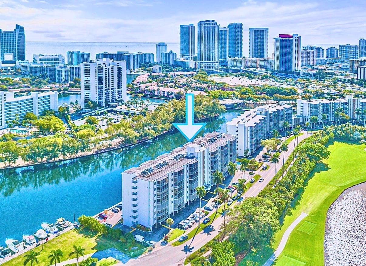400 Diplomat Parkway, #805, Hallandale Beach, FL 33009 Mid-rise waterfront condominium complex featuring private boat slips, balconies with sliding glass doors, exterior parking, and proximity to green space