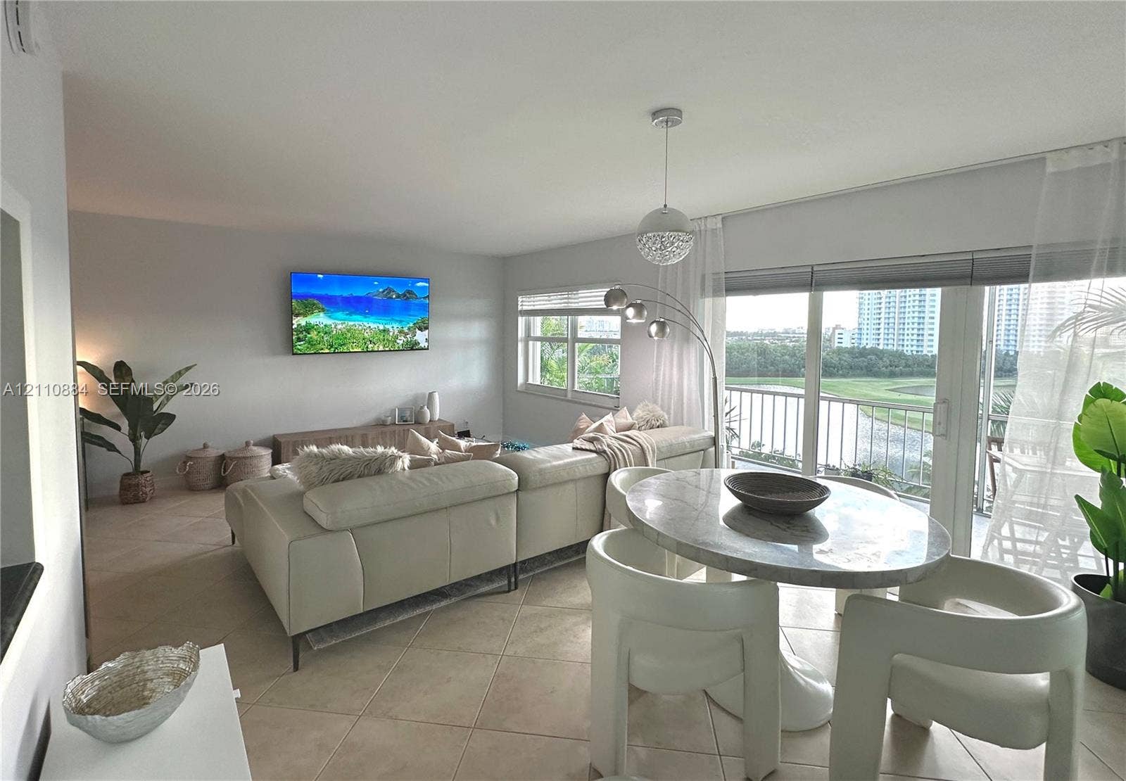 400 Diplomat Parkway, #805, Hallandale Beach, FL 33009 Neutral tile flooring throughout, expansive floor-to-ceiling glass sliding doors, polished pendant lighting, and multiple windows providing natural illumination