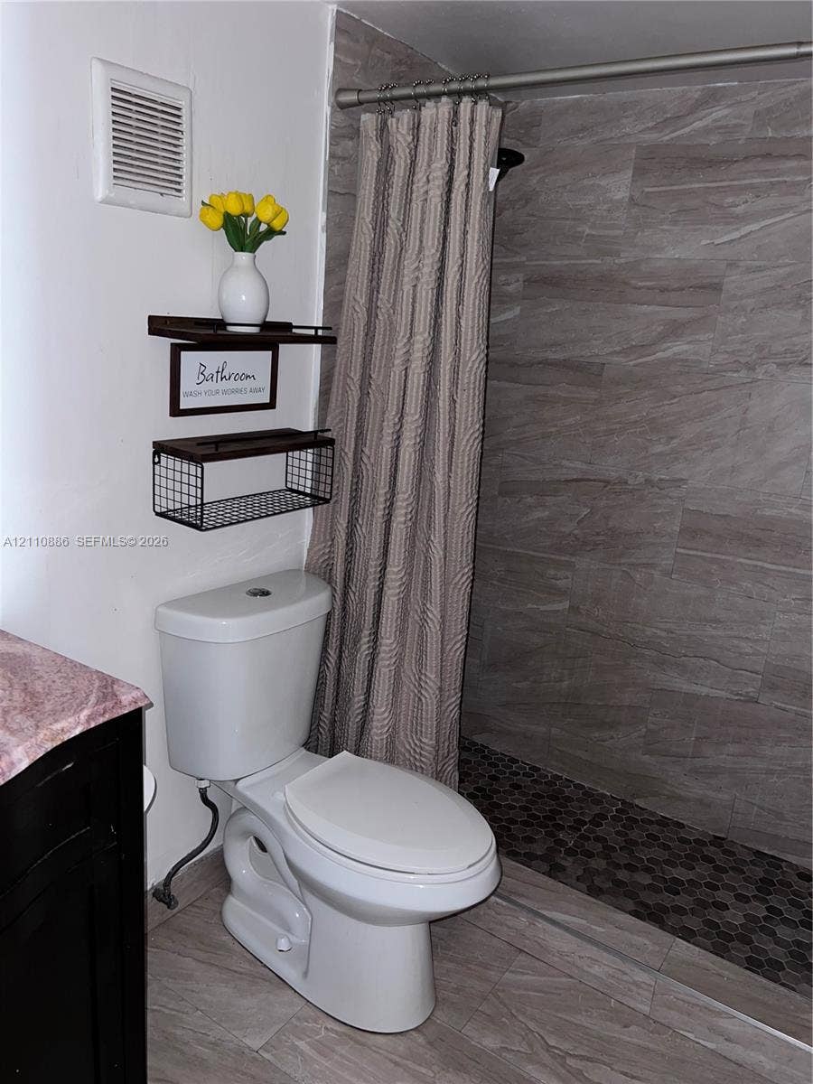 7101 Miami Lakes Drive, #Q12, Miami Lakes, Miami Lakes, FL 33014 Dark-finish vanity featuring an integrated basin, stone-composite countertop, brushed-nickel faucet, and a three-light wall fixture