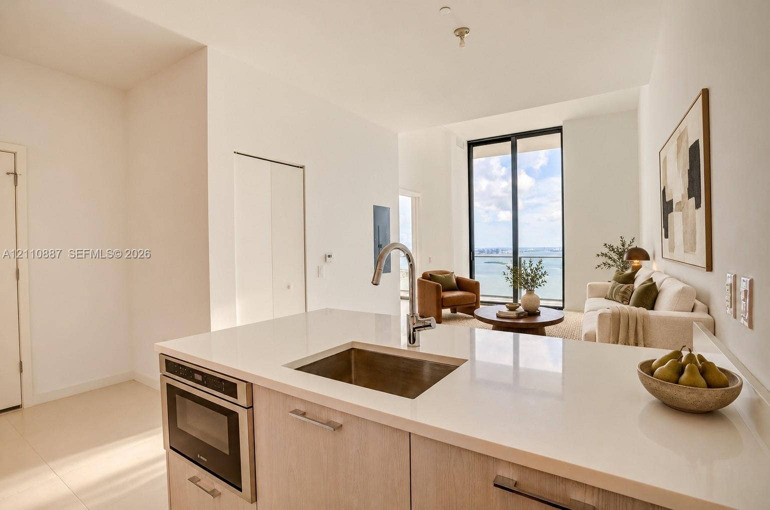 501 NE 31st Street, #4002, Miami, FL 33137 Kitchen featuring a stone countertop, stainless steel undermount sink, high-arc faucet, and built-in microwave, complemented by light-toned cabinetry and expansive floor-to-ceiling windows