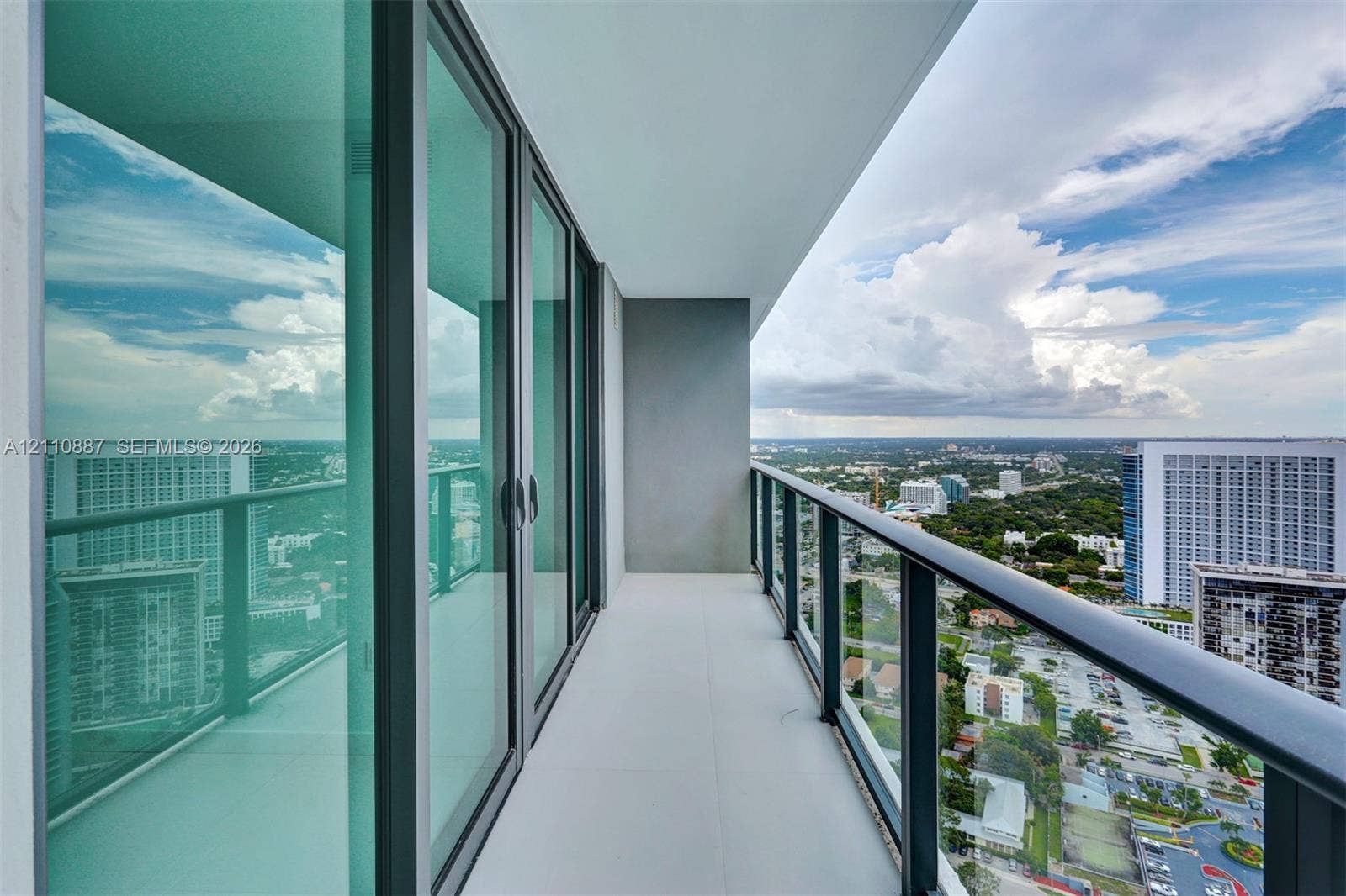 501 NE 31st Street, #4002, Miami, FL 33137 Private balcony featuring floor-to-ceiling glass sliding doors, a metal railing, and neutral tile flooring
