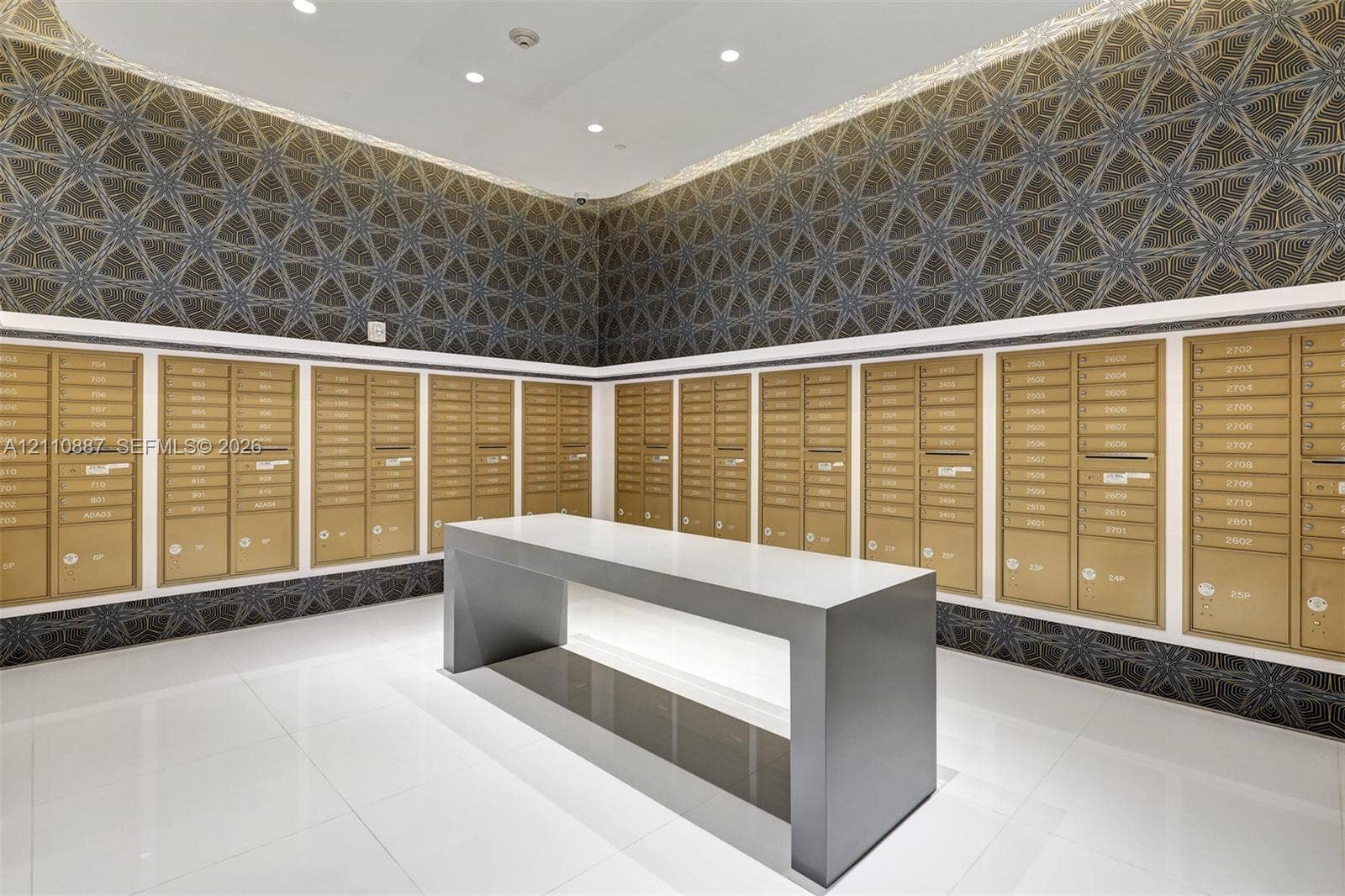 501 NE 31st Street, #4002, Miami, FL 33137 Mail center featuring recessed ceiling lighting, geometric patterned wall covering, polished white floor tiling, and a central freestanding island with a solid surface countertop