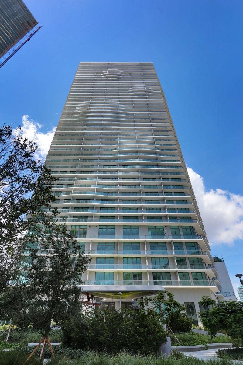 501 NE 31st Street, #4002, Miami, FL 33137 High-rise residential tower featuring a glass facade, undulating exterior balconies, floor-to-ceiling windows, and contemporary architectural design