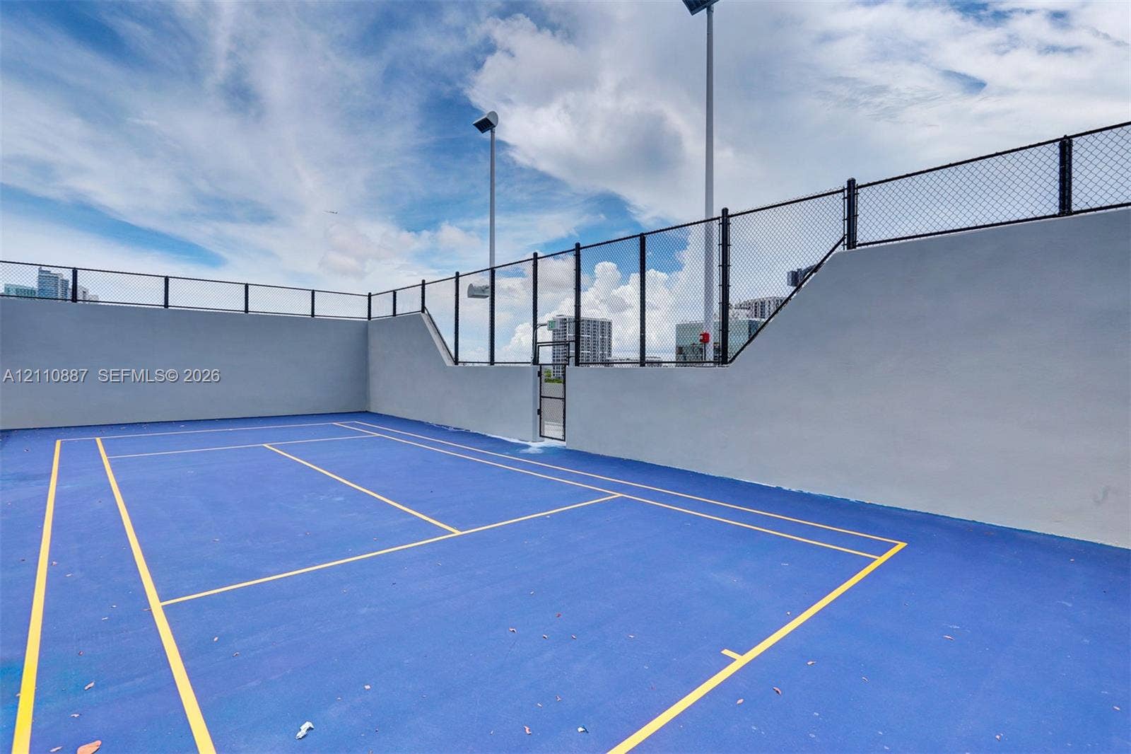 501 NE 31st Street, #4002, Miami, FL 33137 Recreational court featuring a high-contrast surface, perimeter chain-link fencing, solid masonry walls, and integrated court lighting