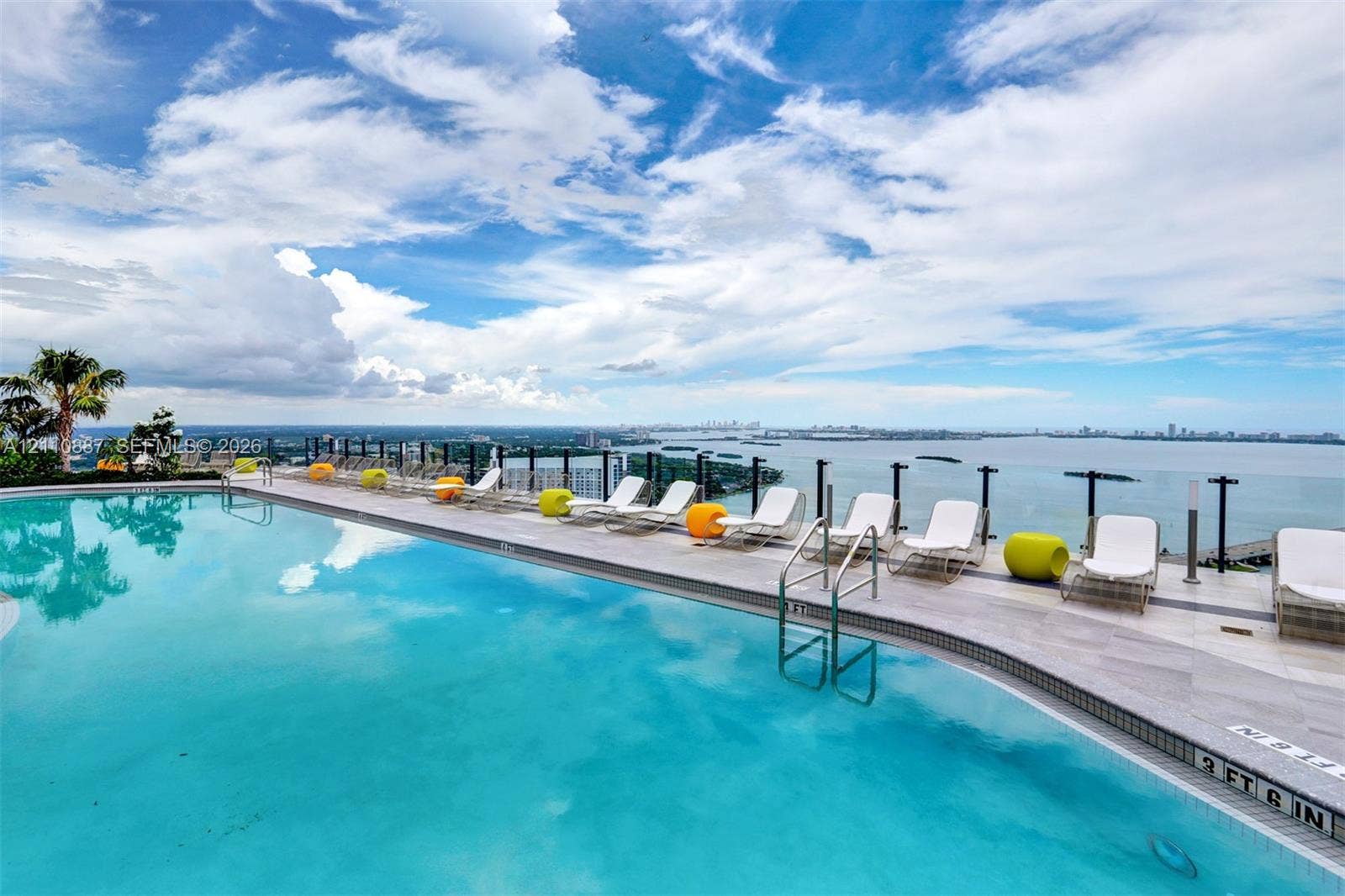 501 NE 31st Street, #4002, Miami, FL 33137 Infinity-edge swimming pool featuring a tile surround, metal safety railing, and deep water finish