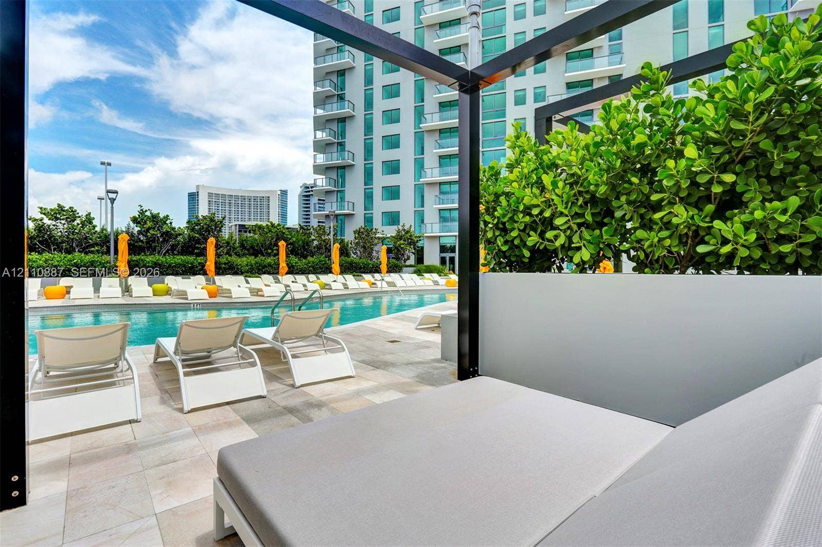 501 NE 31st Street, #4002, Miami, FL 33137 Outdoor swimming pool featuring stone-tiled decking, black metal pergola structures, and integrated privacy partitions