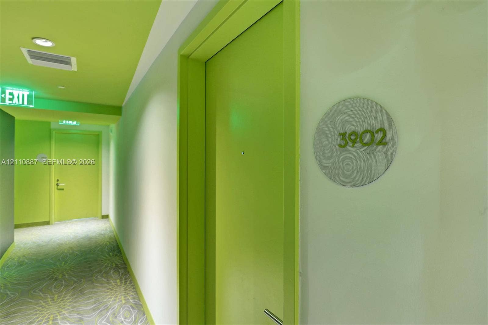 501 NE 31st Street, #4002, Miami, FL 33137 Hallway featuring lime-toned door frames, recessed ceiling lighting, patterned wall-to-wall carpeting, and circular suite identification signage