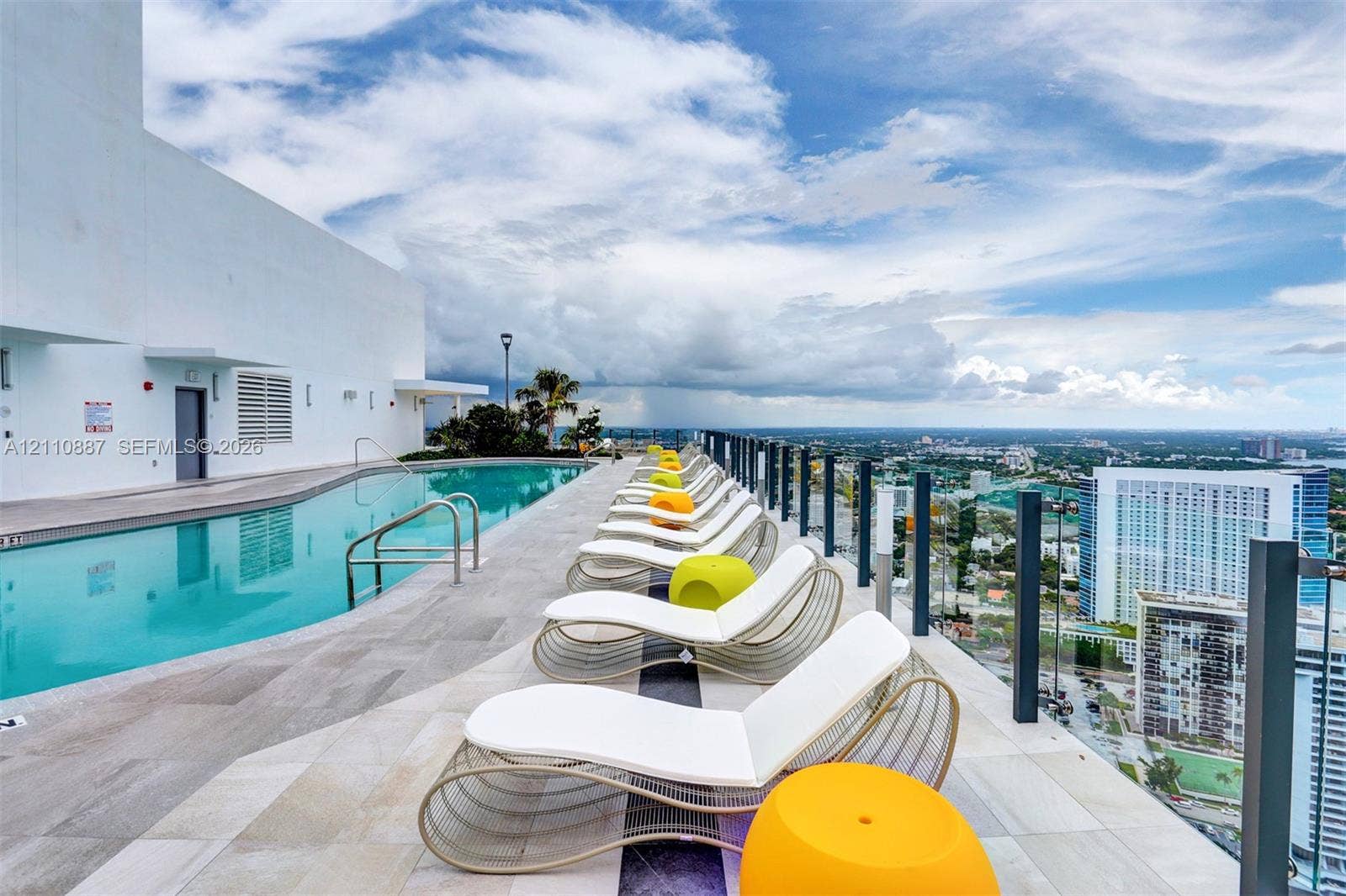 501 NE 31st Street, #4002, Miami, FL 33137 Rooftop swimming pool featuring stone-tile decking, metal safety railings, and expansive urban scenery