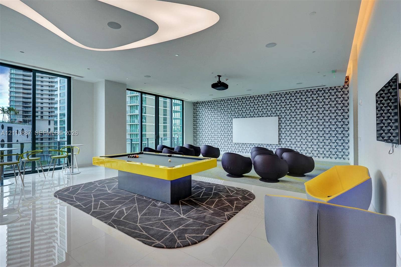 501 NE 31st Street, #4002, Miami, FL 33137 Contemporary media room featuring a sculptural ceiling fixture, patterned accent wall, floor-to-ceiling windows, and glossy stone-finish flooring