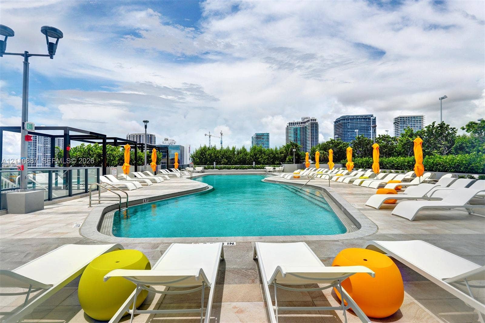 501 NE 31st Street, #4002, Miami, FL 33137 Rooftop swimming pool featuring stone deck surfacing, metal perimeter fencing, and integrated lighting fixtures