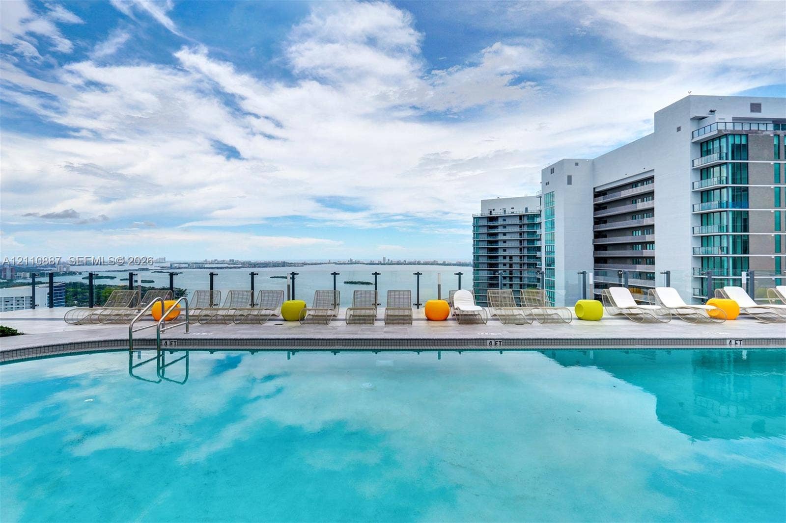 501 NE 31st Street, #4002, Miami, FL 33137 Rooftop swimming pool featuring a tiled deck, glass panel railings, and horizon water scenery