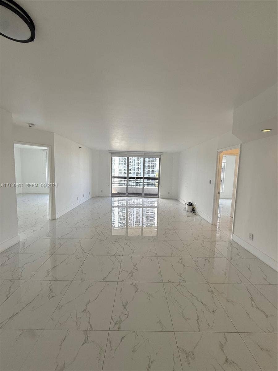 3600 Mystic Pointe Drive, #1611, Aventura, FL 33180 Large-format white tile flooring with grey veining, neutral wall finishes, recessed lighting, and floor-to-ceiling sliding glass doors featuring a metal frame