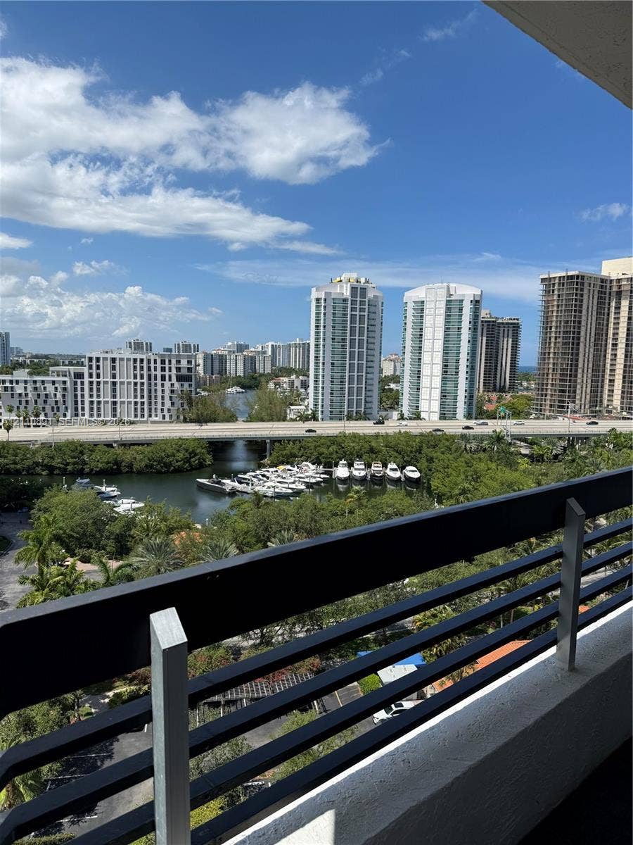 3600 Mystic Pointe Drive, #1611, Aventura, FL 33180 Balcony featuring horizontal black metal railing overlooking a waterway, marina with docked boats, and urban cityscape