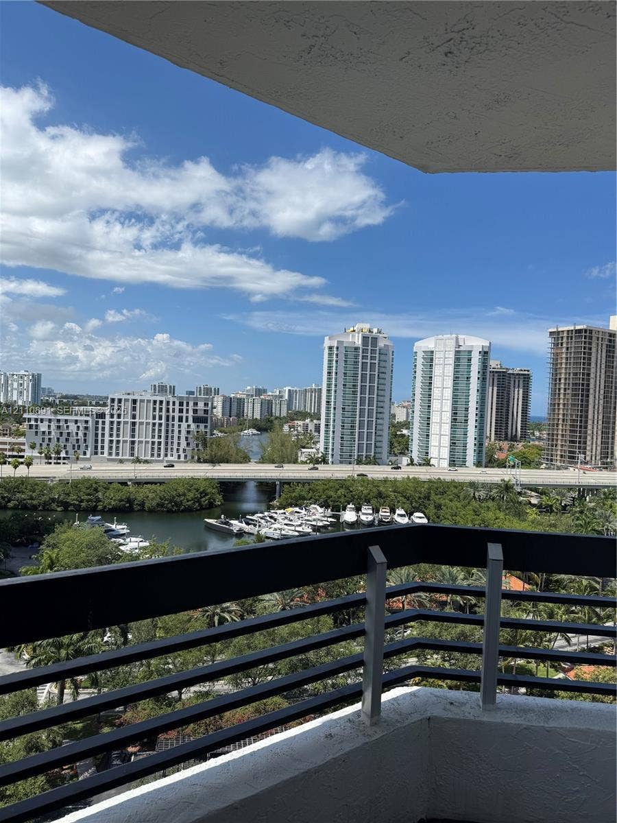 3600 Mystic Pointe Drive, #1611, Aventura, FL 33180 Private balcony featuring a black metal railing overlooking a waterway, boat slips, and an urban cityscape