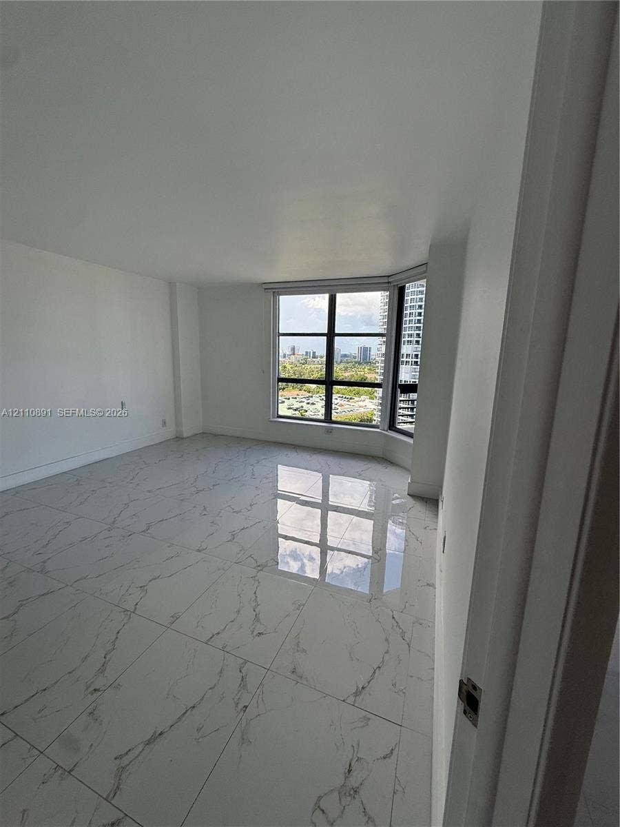 3600 Mystic Pointe Drive, #1611, Aventura, FL 33180 Large-format polished tile flooring, floor-to-ceiling windows with grid detailing, and panoramic urban scenery