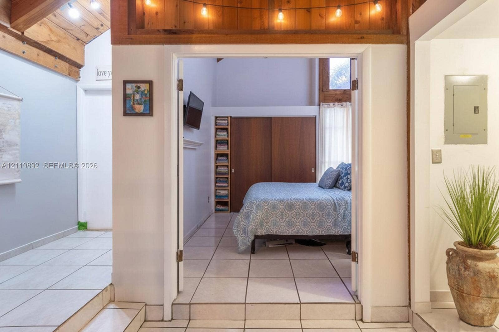 497 N University Drive, #2-7, Plantation, FL 33324 Vaulted ceiling with exposed wood beams, tile flooring, built-in shelving, and dual-panel wood sliding closet doors
