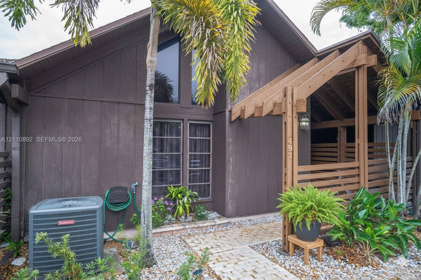 497 N University Drive, #2-7, Plantation, FL 33324 Vertical wood-paneled exterior, A-frame architectural detailing, oversized trapezoidal window, and timber-frame covered entryway with built-in latticework